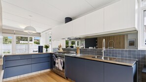 Una cocina moderna con una isla central, electrodomésticos de acero inoxidable y vistas al exterior.