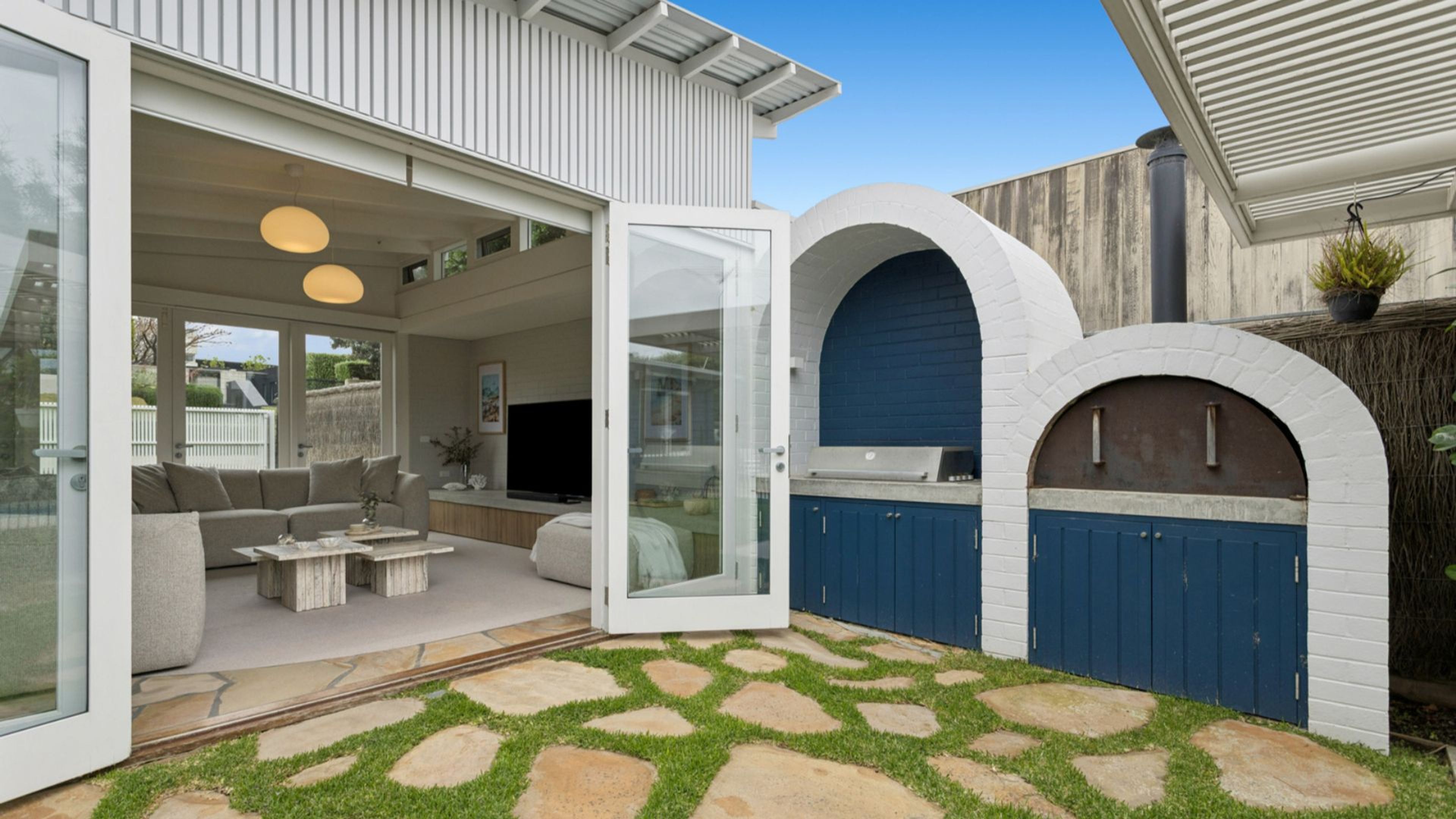 Een modern huis met een glazen deur die uitkomt op een patio met buitenmeubilair.