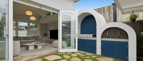 Een modern huis met een glazen deur die uitkomt op een patio met buitenmeubilair.