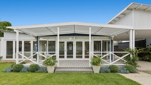 A modern house with a covered porch, large windows, and a well-maintained lawn.