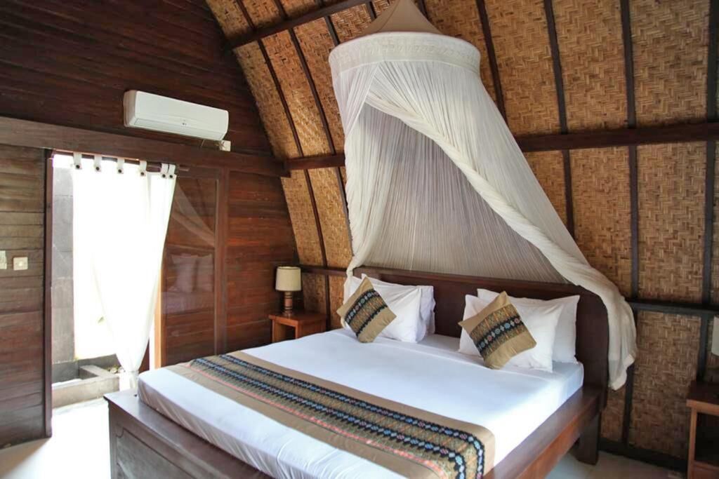 A room with a bed, a nightstand, a lamp, and a mosquito net.