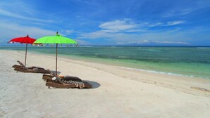 A beach with lounge chairs and umbrellas. - Unzipp Lumbung (Gili Trawangan)