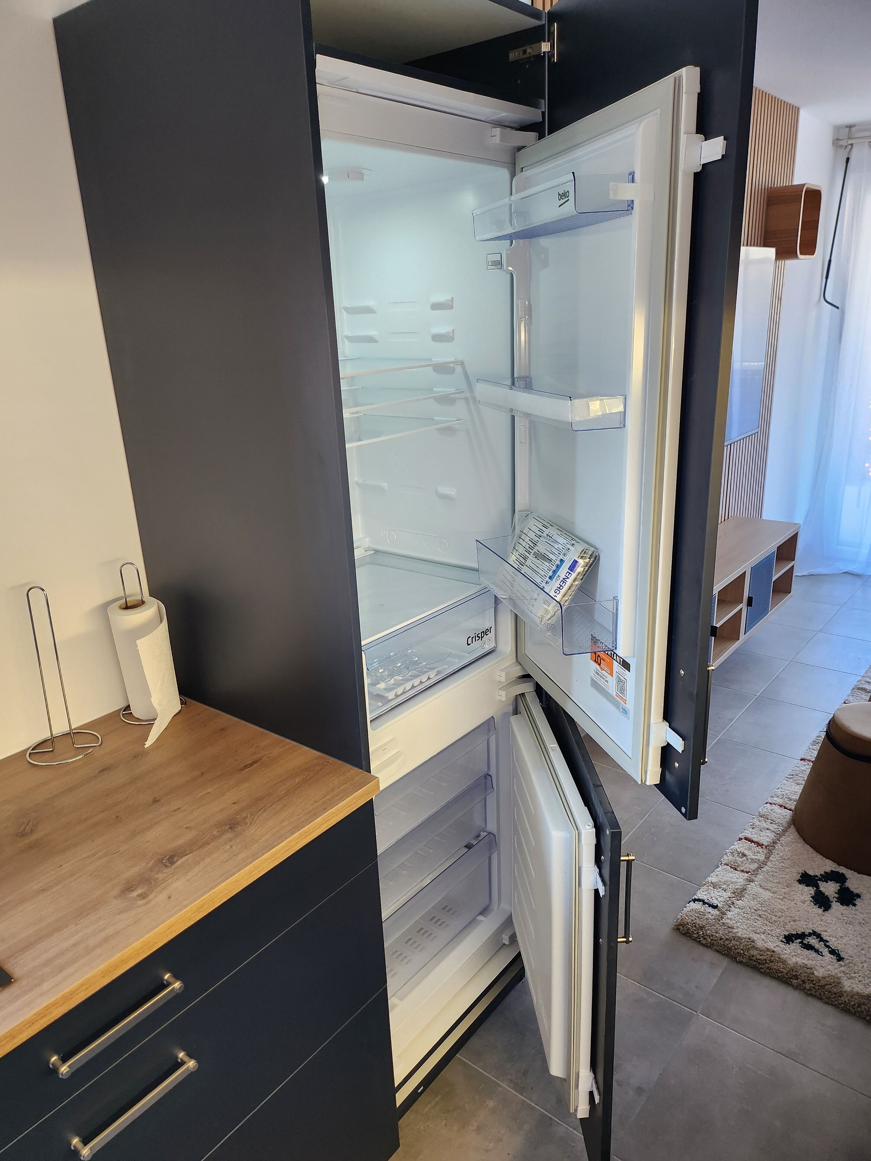 A modern kitchen with a built-in refrigerator, a wooden countertop, and a small sink.