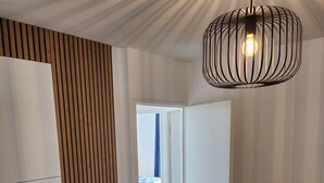 A modern dining area with a black table set for four, white chairs, and a hanging light fixture. - Upscale 2-bathroom apartment (Toulouse)