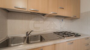 A kitchen with wooden cabinets, a stainless steel sink, and a gas stove. - IL BORGHETTO - BILOCALE IL BORGHETTO (Campo nell'Elba)