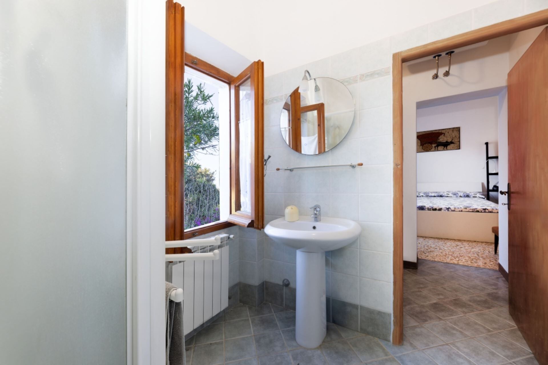 A bathroom with a window, a sink, and a mirror.