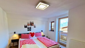 A bedroom with a bed, two bedside tables, a window, and wall decorations. - Almluft by Interhome (Weerberg)