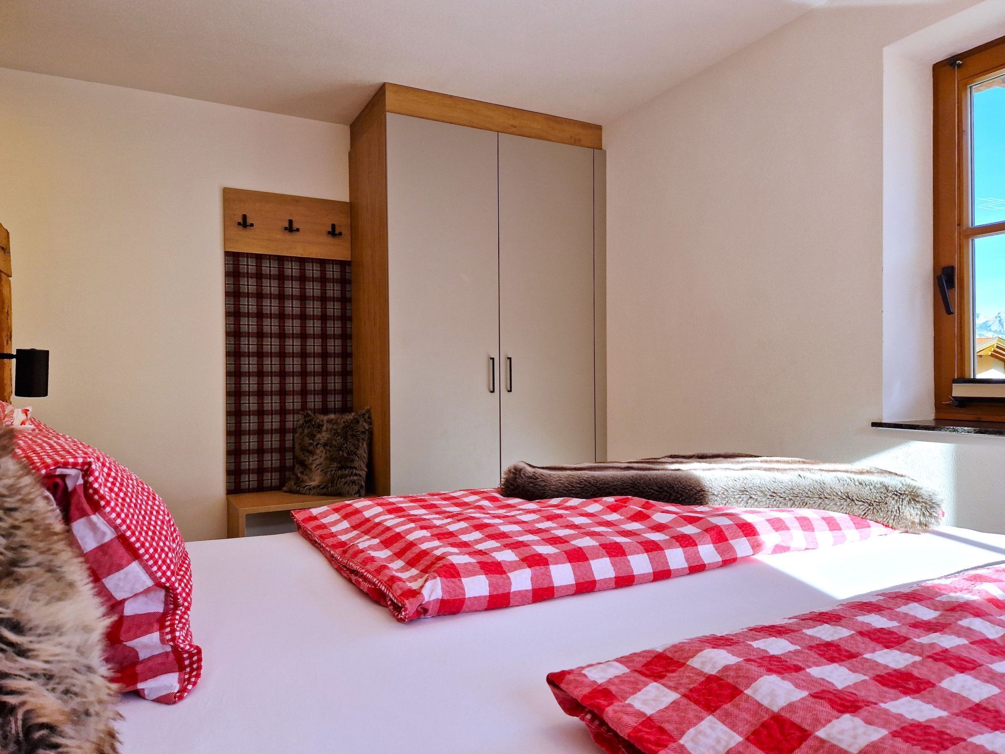 Een slaapkamer met een bed, een kledingkast, een raam en uitzicht op het omliggende landschap.