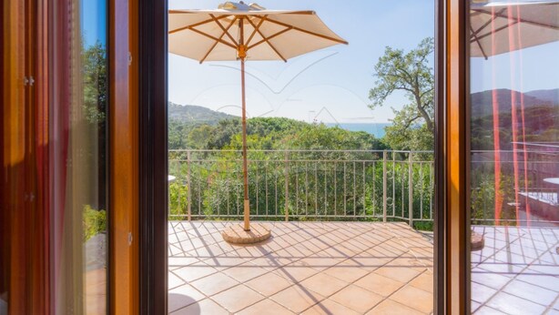 Un balcón con vistas a un paisaje verde y exuberante y al mar.
