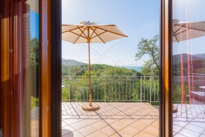 Un balcon offrant une vue sur un paysage verdoyant et luxuriant ainsi que sur la mer.