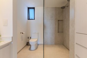 Ein modernes Badezimmer mit Toilette, kleinem Fenster und Duschbereich.