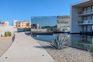 Ein modernes Gebäude mit Glasfassade, Pool und einem Betonweg.