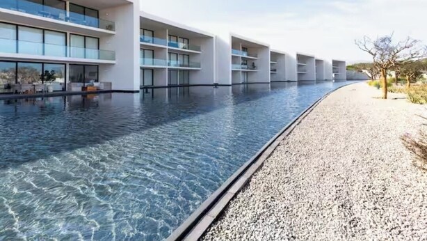 Ett modernt hotell med en lång pool som ligger intill en byggnad med flera balkonger.