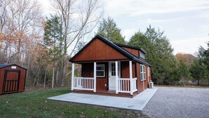 Eine kleine Holzhütte mit Veranda, einer Tür und einem Fenster.