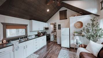 A kitchen with white cabinets, a wooden ceiling, and a ceiling fan.
