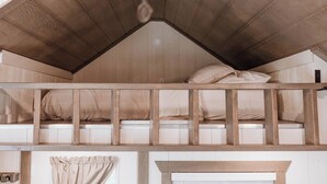 Ein Stockbett mit Holzboden und einem Fenster mit Vorhängen.