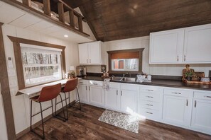 A kitchen with white cabinets, a wooden ceiling, and a window.