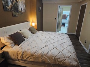 A bedroom with a large bed, a bedside table, a nightstand, and a wall-mounted lamp. - Outskirts of Gatlinburg, Minutes to everything 3-bedroom apartment in Gatlinburg (Gatlinburg)