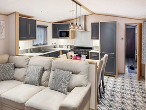 Een moderne keuken met donkere kastjes, een fornuis en een zithoek met een bank en stoelen.