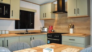 Una cocina moderna con una mesa de madera, sillas tapizadas en gris y una estufa empotrada.