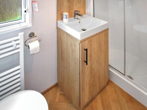 A bathroom with a white sink, wooden cabinet, and a toilet. - This three-bedroom lodge at Beverley Holiday Park, Paignton. (Paignton)