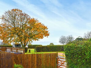 A wooden fence, a tree with orange leaves, and a clear sky. - This three-bedroom lodge at Beverley Holiday Park, Paignton. (Paignton)