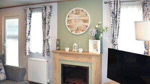 Una sala de estar con chimenea, televisor y sofá.