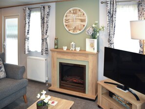 A living room with a fireplace, a television, and a sofa. - This three-bedroom lodge at Beverley Holiday Park, Paignton. (Paignton)