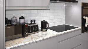 Eine moderne Küche mit einem schwarzen Induktionskochfeld, einer Kaffeemaschine und einem Toaster.