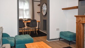 Ein modernes Wohnzimmer mit türkisfarbenen Sofas, einem Holztisch und einem Essbereich mit Tisch und Stühlen.