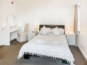 Ein ordentlich eingerichtetes Hotelzimmer mit Bett, Nachttischen, Schreibtisch, Stuhl und Spiegel.