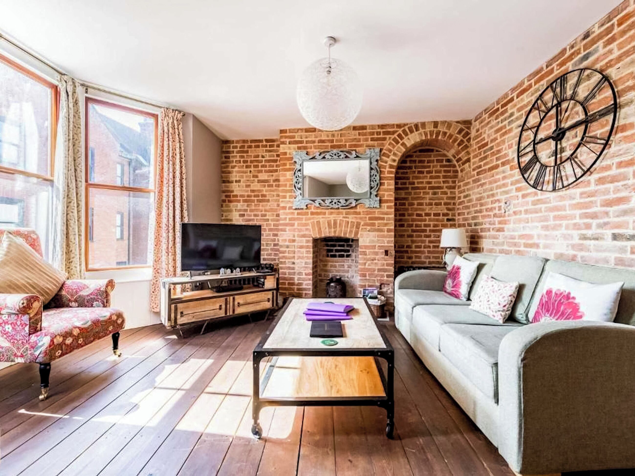 Una sala de estar con pared de ladrillo, chimenea, televisor, sofá y mesa de centro.