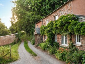 A stone building with ivy-covered walls and a gravel path leading to it. - 3 bedroom accommodation in Cadbury (Cadbury)