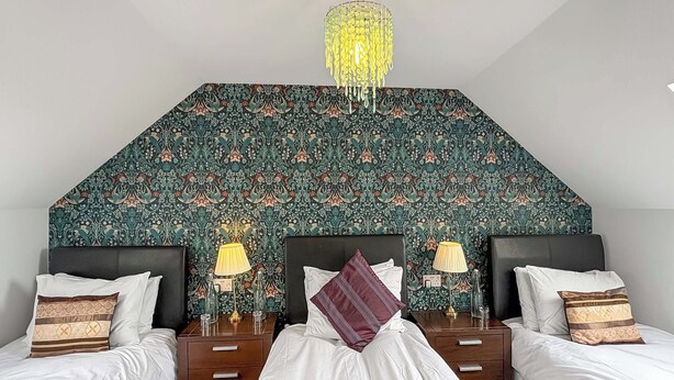 A bedroom with two beds, a patterned ceiling, and a chandelier. - 8 bedroom accommodation in Dingwall (Dingwall)
