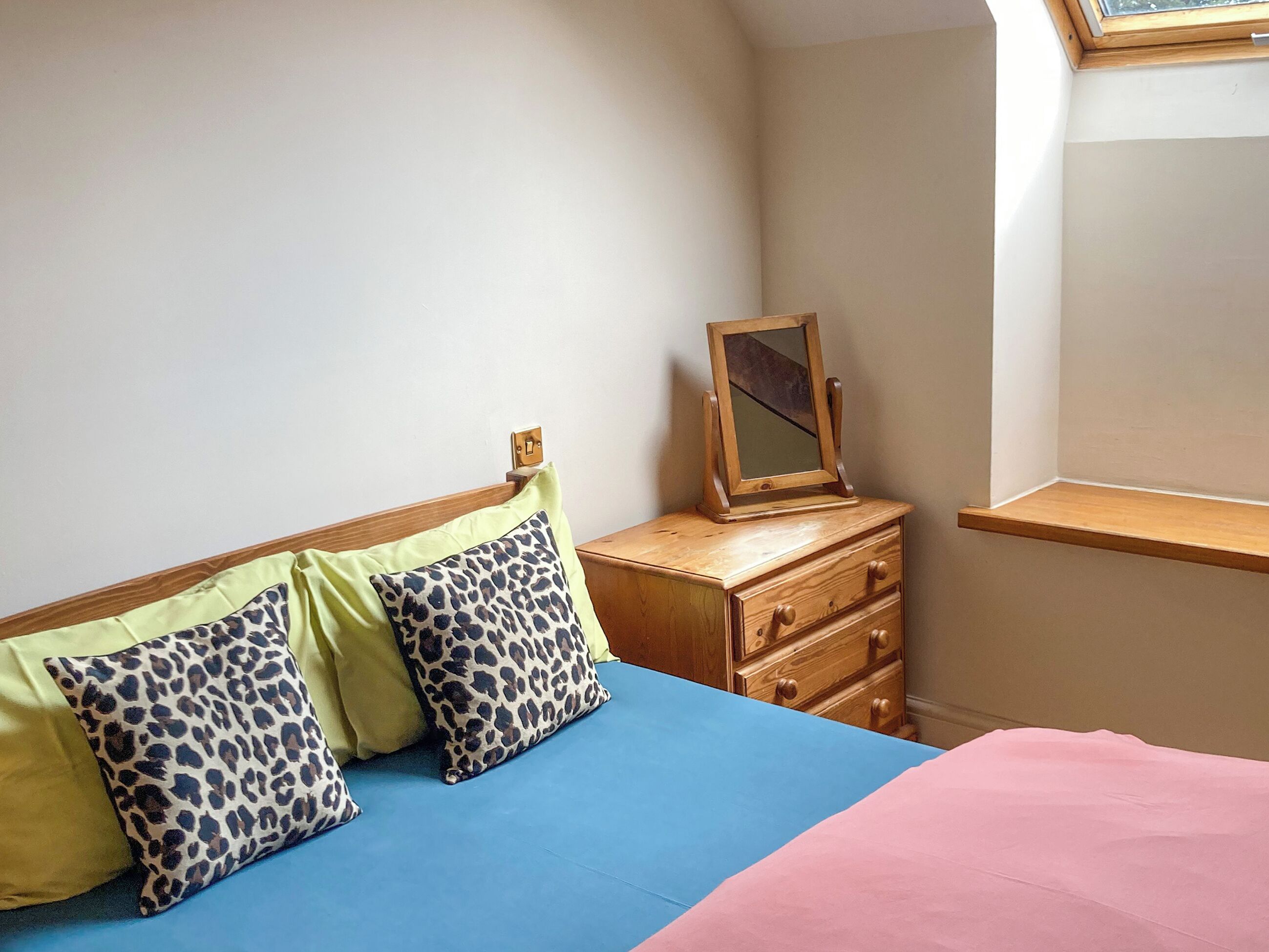 Une chambre à coucher avec un lit, une commode, un miroir et une fenêtre.