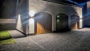 En bygning med tre buede indgange, en grusvej og udendørsbelysning.