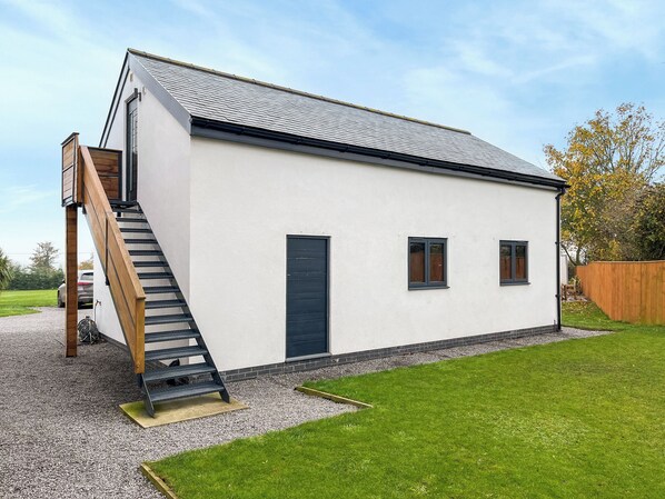 A white building with a sloped roof, a wooden staircase, and a small front yard. - 1 bedroom accommodation in Brompton On Swale, near Richmond (Brompton On Swale, near Richmond)