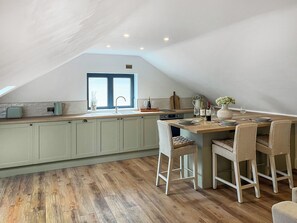 A kitchen with a central island, a dining area with chairs, and a window with a view.