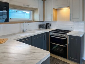 A kitchen with a sink, stove, oven, and a window above the sink. - 2 bedroom accommodation in Filey (Filey)