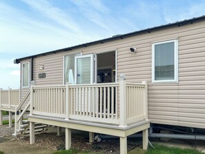 A mobile home with a balcony, a staircase, and a window with a shutter. - 2 bedroom accommodation in Filey (Filey)