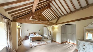 A bedroom with a wooden ceiling, a bed, a dresser, and a mirror. - 4 bedroom accommodation in Olney (Olney)