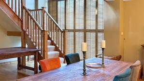 A dining area with a wooden table, chairs, and a staircase. - 4 bedroom accommodation in Olney (Olney)