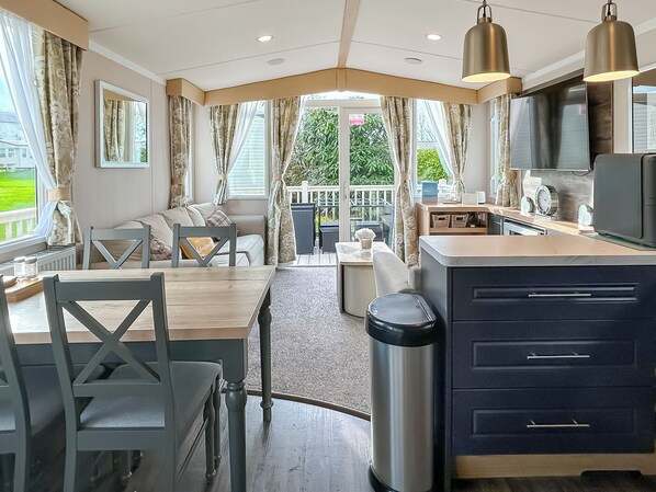 A modern kitchen with a dining area, large windows, and a view of the outdoors.