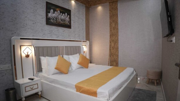 Un dormitorio moderno con una cama grande, mesitas de noche, un televisor montado y un cuadro en la pared.