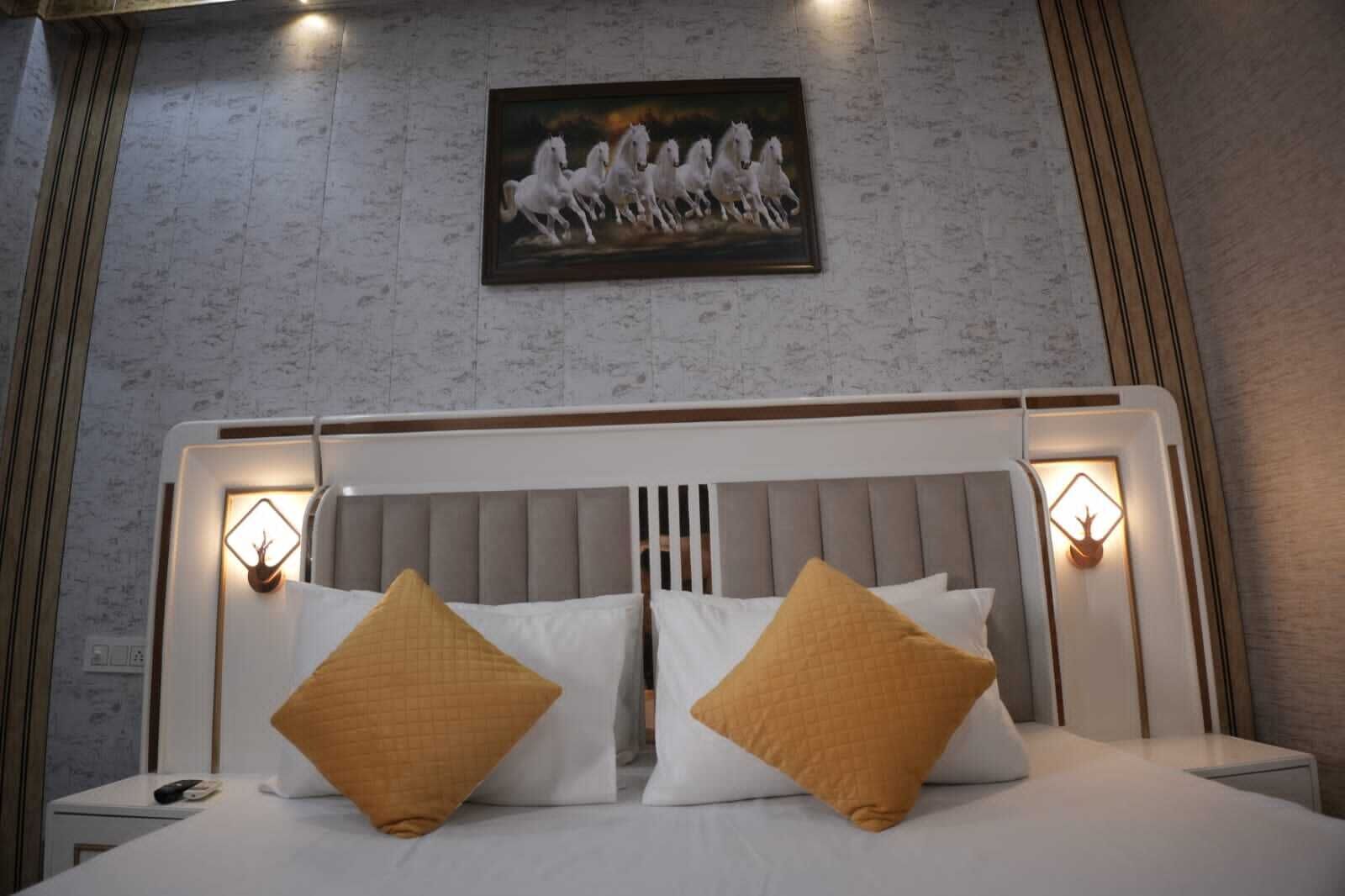A neatly made bed with two pillows, a headboard with built-in lighting, and a painting of horses on the wall.