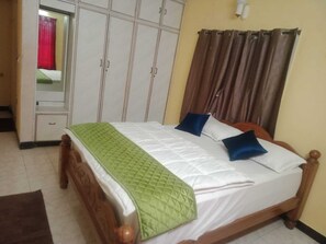 Una cama bien tendida con un edredón verde, un cabecero de madera y dos almohadas.