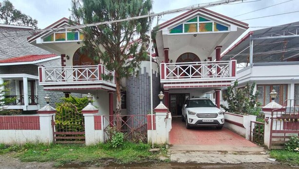 A two-story house with a balcony, a gated entrance, and a parked car. - Sunshine Royale (Kodaikanal)