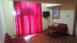 A living room with a sofa, a coffee table, and a TV mounted on the wall. - Sunshine Royale (Kodaikanal)