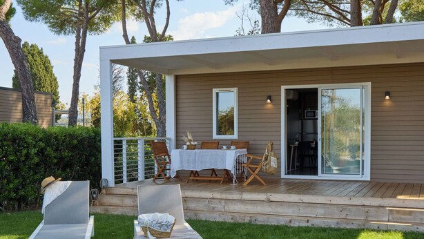 Een modern buitenterras met een tafel, stoelen, een terras en lounge fauteuils.