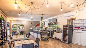 Een restaurant met houten vloeren, tafels met stoelen, een bar en planken met flessen.